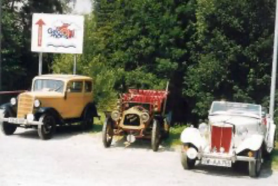 Drei historische Autos stehen nebeneinander am Straßenrand.