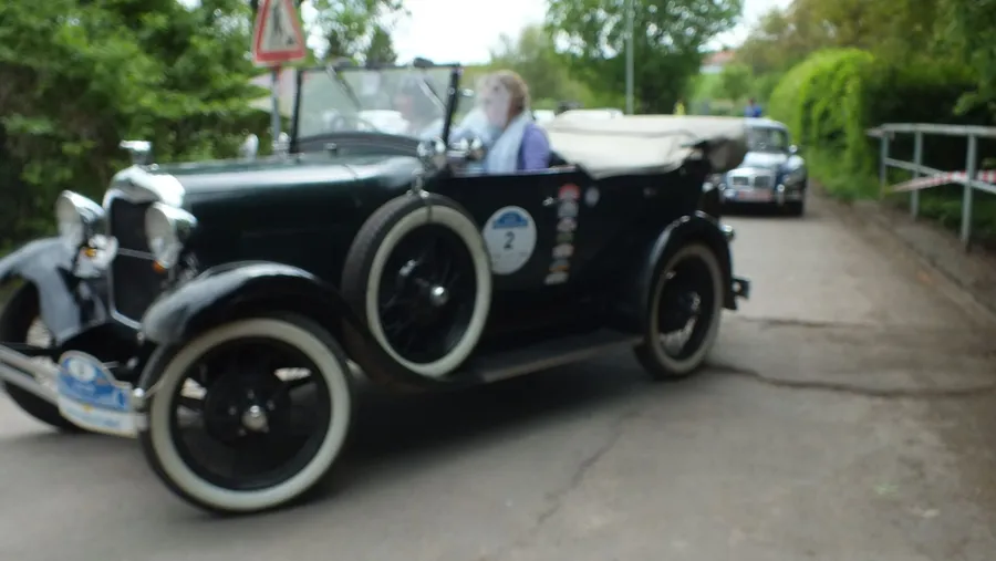 Schwarzer offener Tourenwagen aus den 1920er-Jahren auf der Straße.