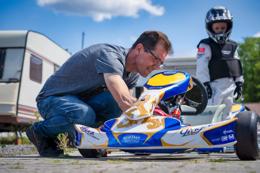 Ein Trainer stellt das Kart ein, daneben wartet ein Kind mit Helm.