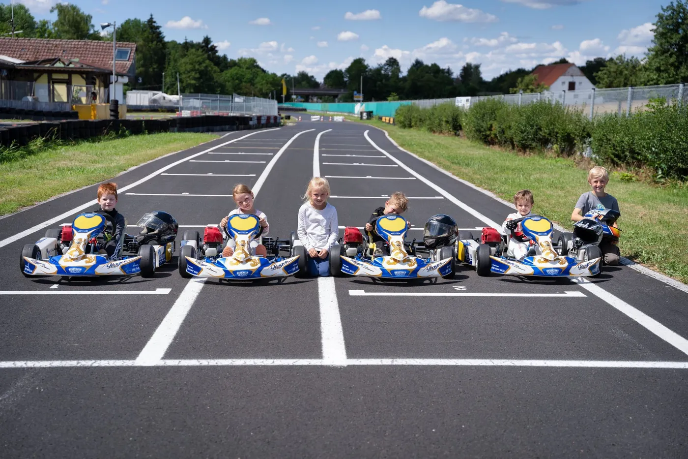 Fünf Kinder sitzen lachend in ihren Puffo-Karts nebeneinander in der Startaufstellung.