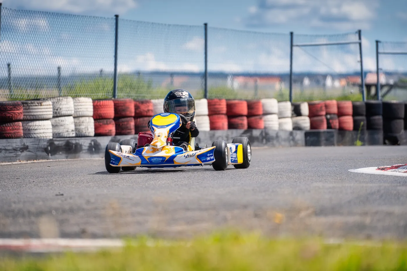 Kind mit Helm fährt ein blau-gelbes Puffo-Kart über die Strecke.