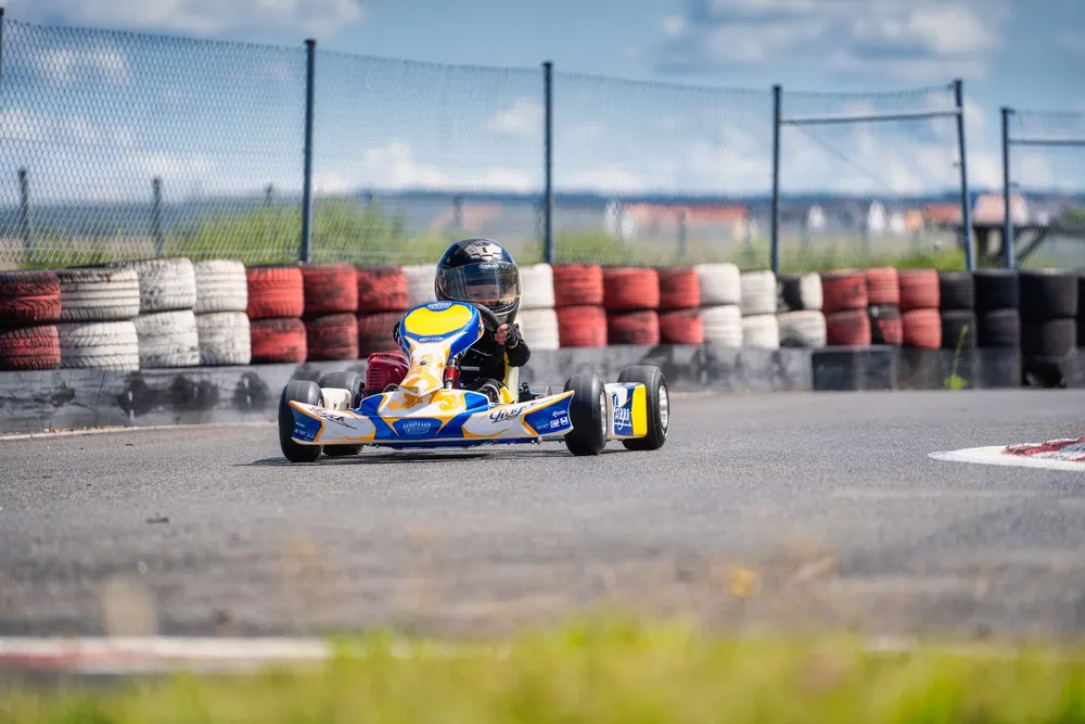 Kind mit Helm fährt ein blau-gelbes Puffo-Kart über die Strecke.